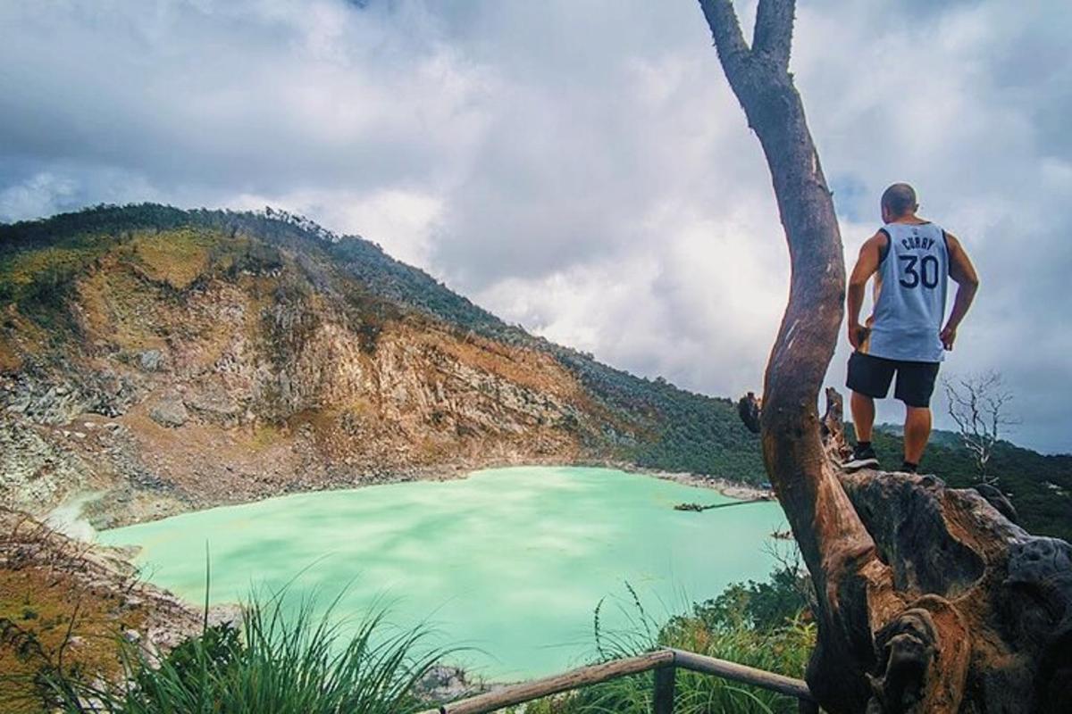 Un hombre parado en una colina mirando un lago verde