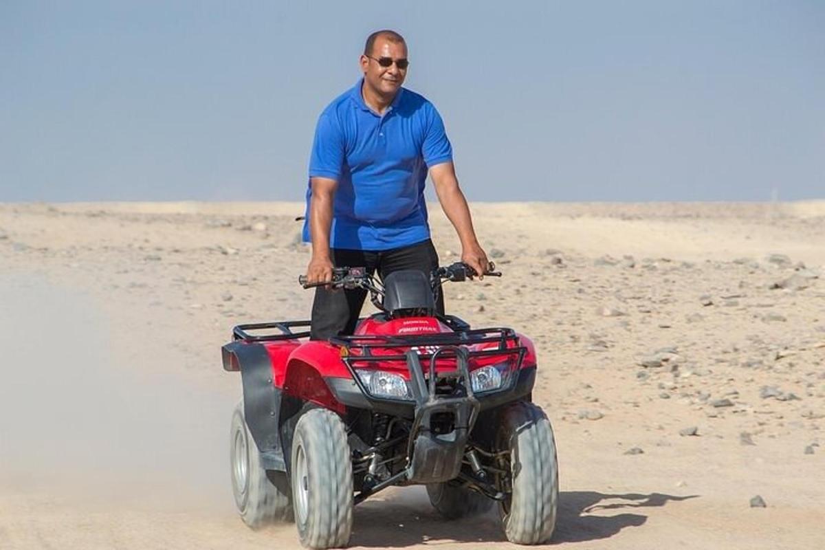 Un hombre parado en un vehículo de cuatro ruedas en la playa