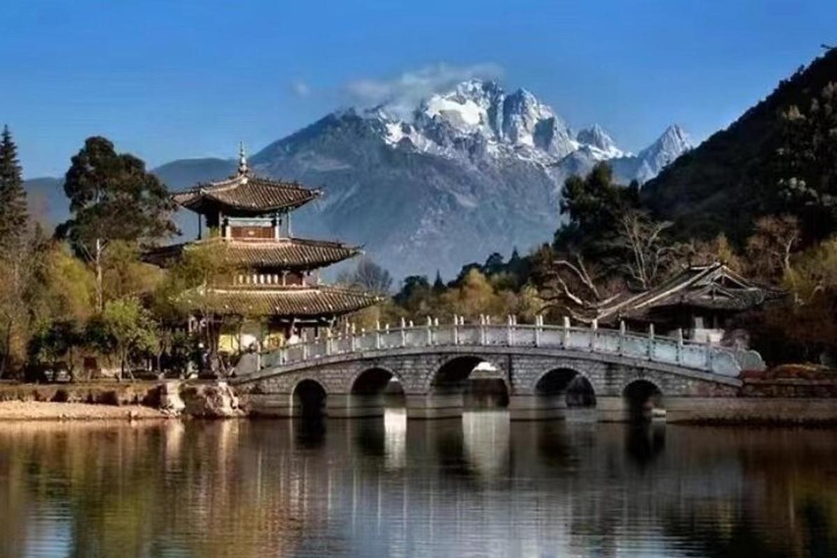 a bridge over a lake in front of a mountain