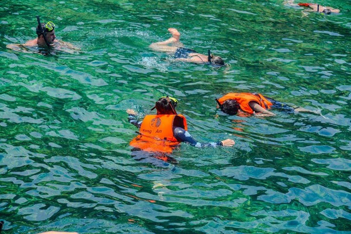 sekumpulan orang di dalam air memakai jaket keselamatan