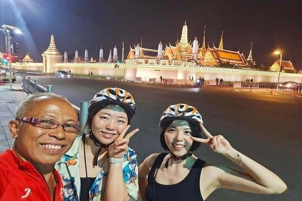 một người đàn ông và hai người phụ nữ đang tạo dáng trước một tòa nhà
