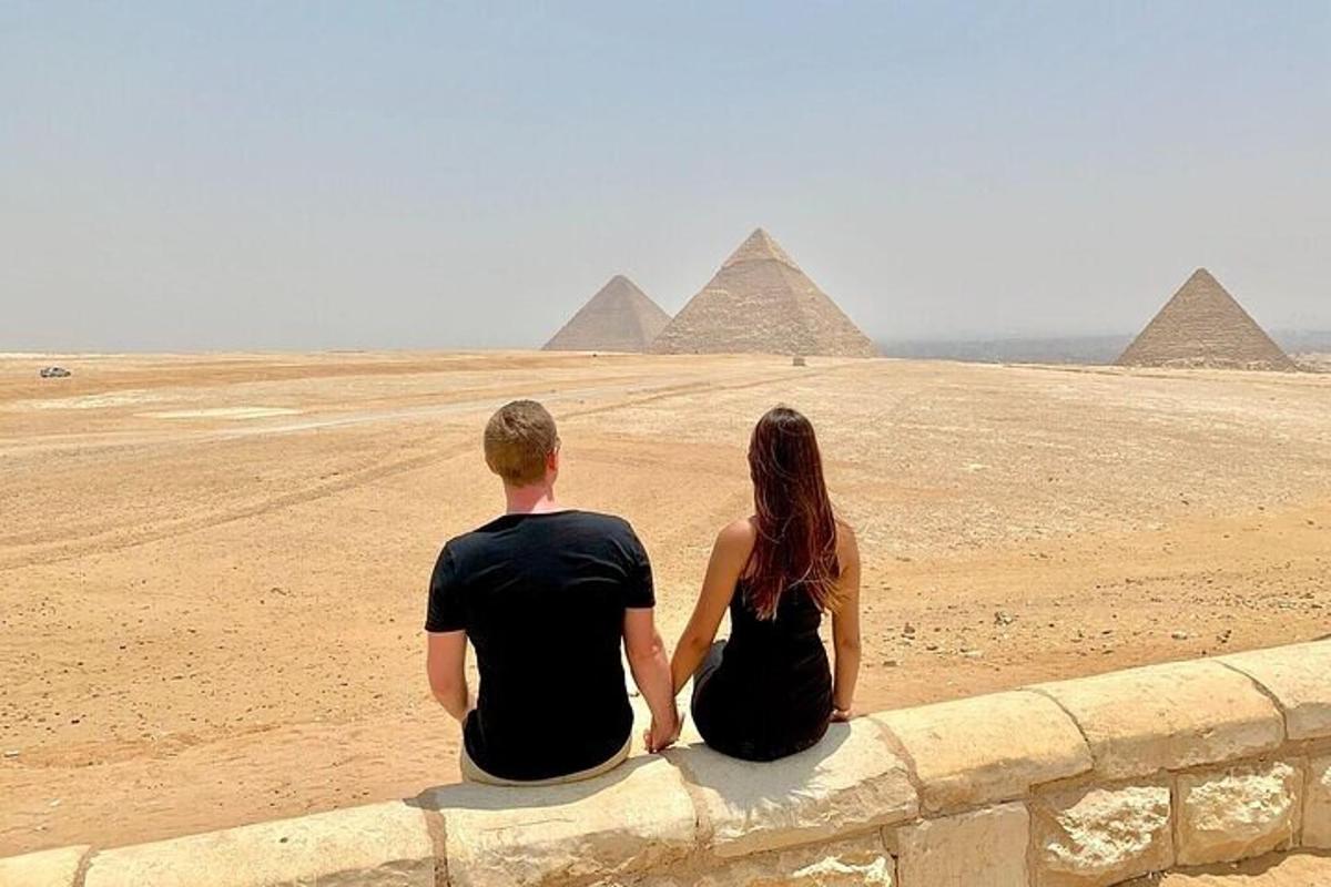 muž a žena sedící na zdi a dívající se na pyramidy