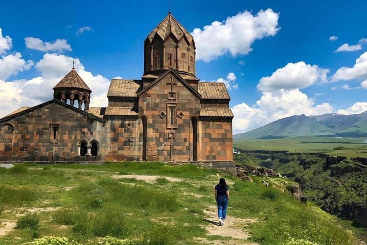 una donna che cammina verso una vecchia chiesa su una collina