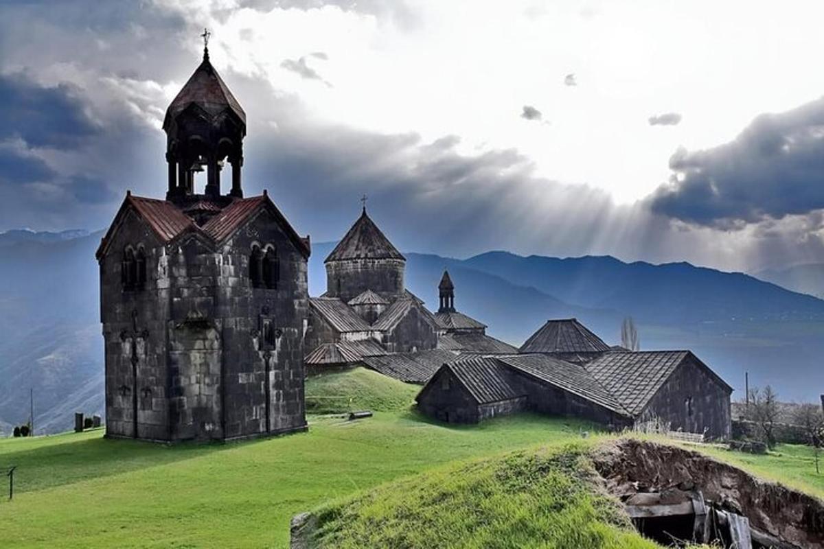 eine alte Kirche auf einer grünen Wiese mit Bergen im Hintergrund