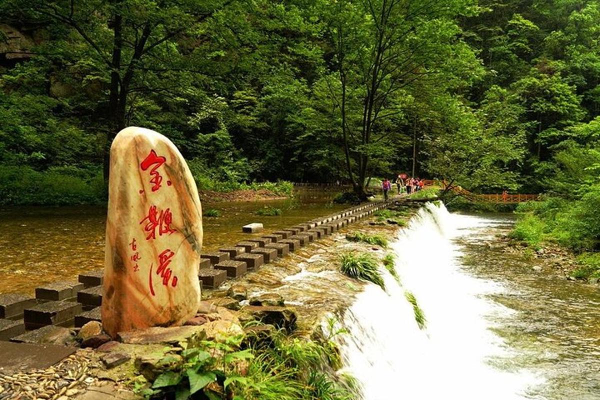 uma estátua de pedra ao lado de um rio com uma cachoeira