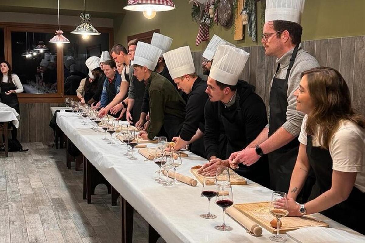 un grup de bucătari stând în jurul unei mese lungi cu pahare de vin