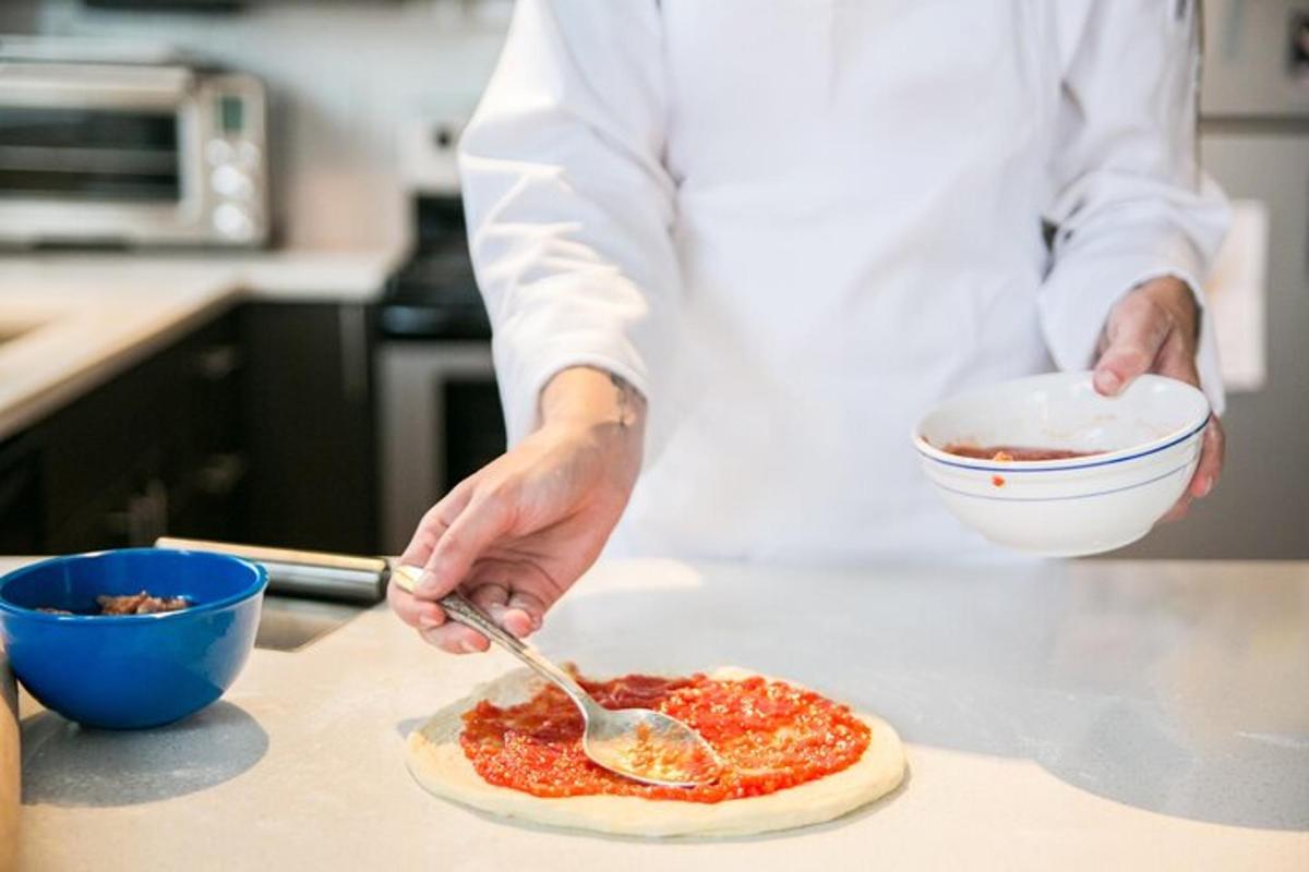 un home a la cuina preparant una pizza