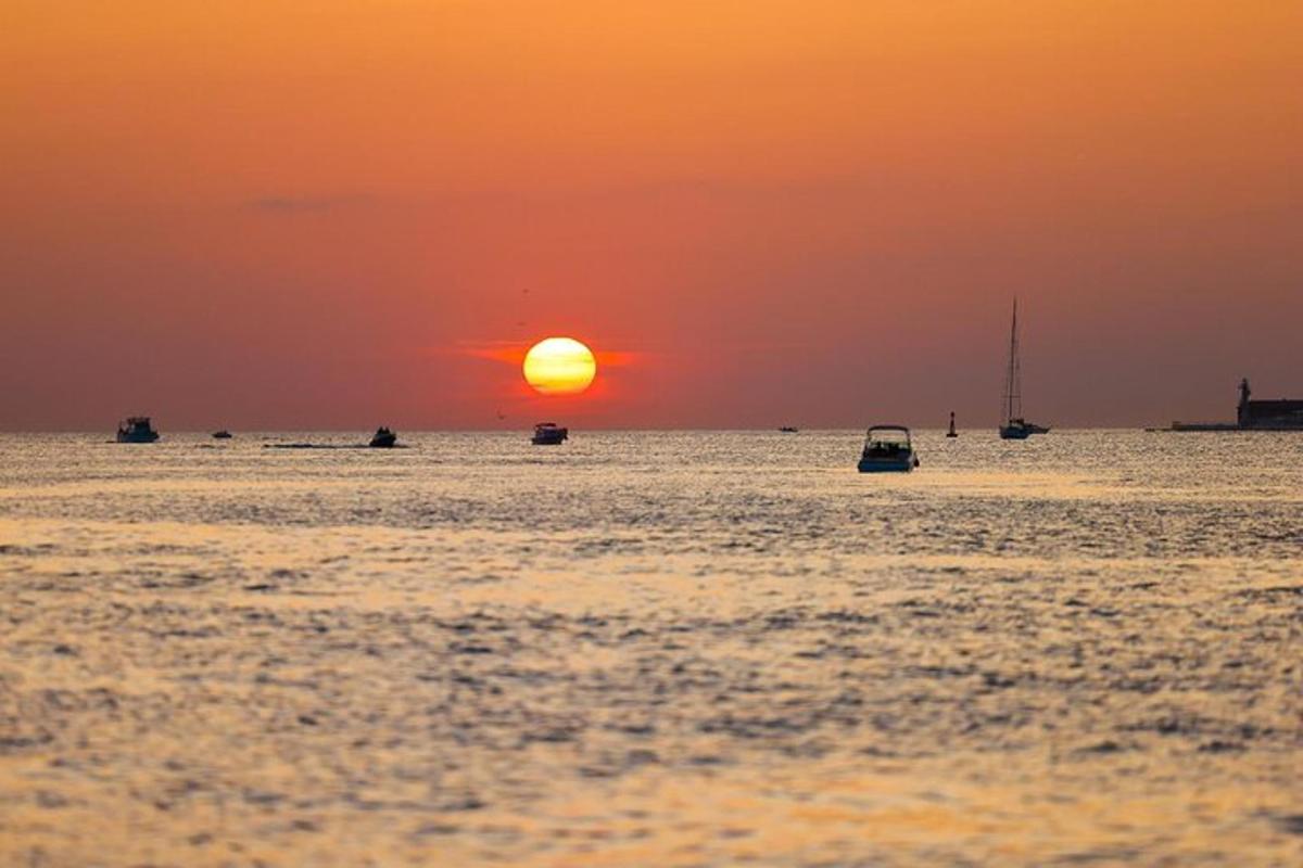 sončni zahod nad oceanom s čolni v vodi