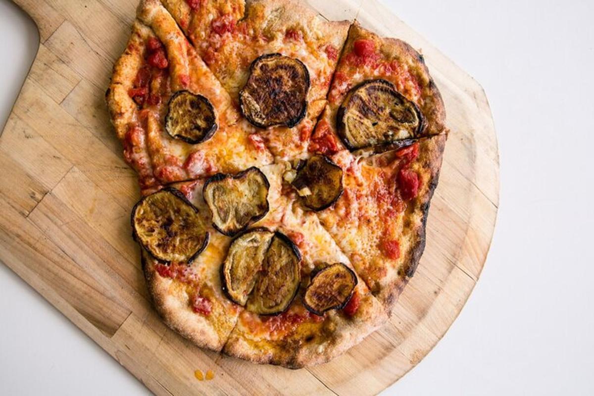 pizza yang terletak di atas papan pemotong kayu