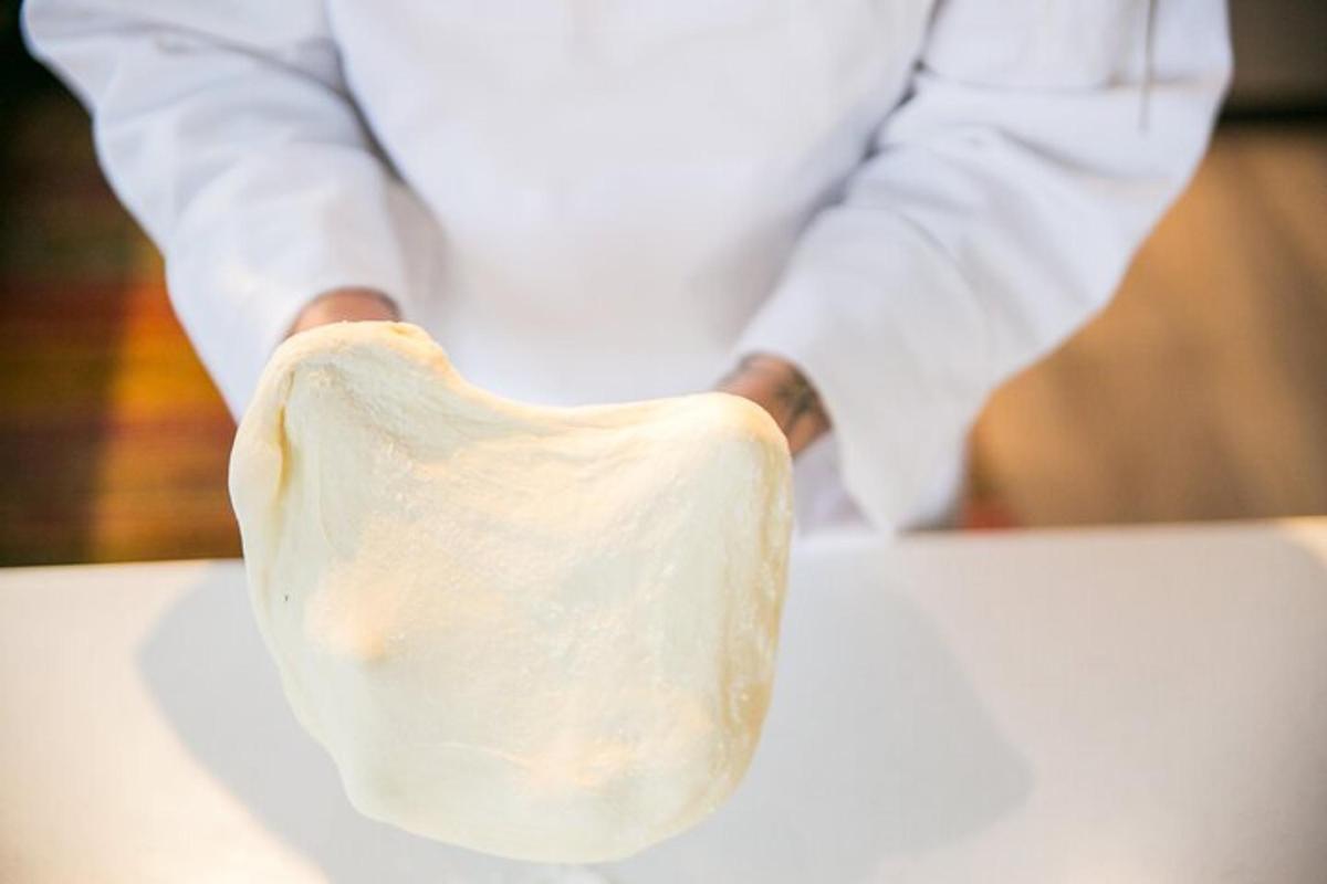 a chef is holding a piece of dough