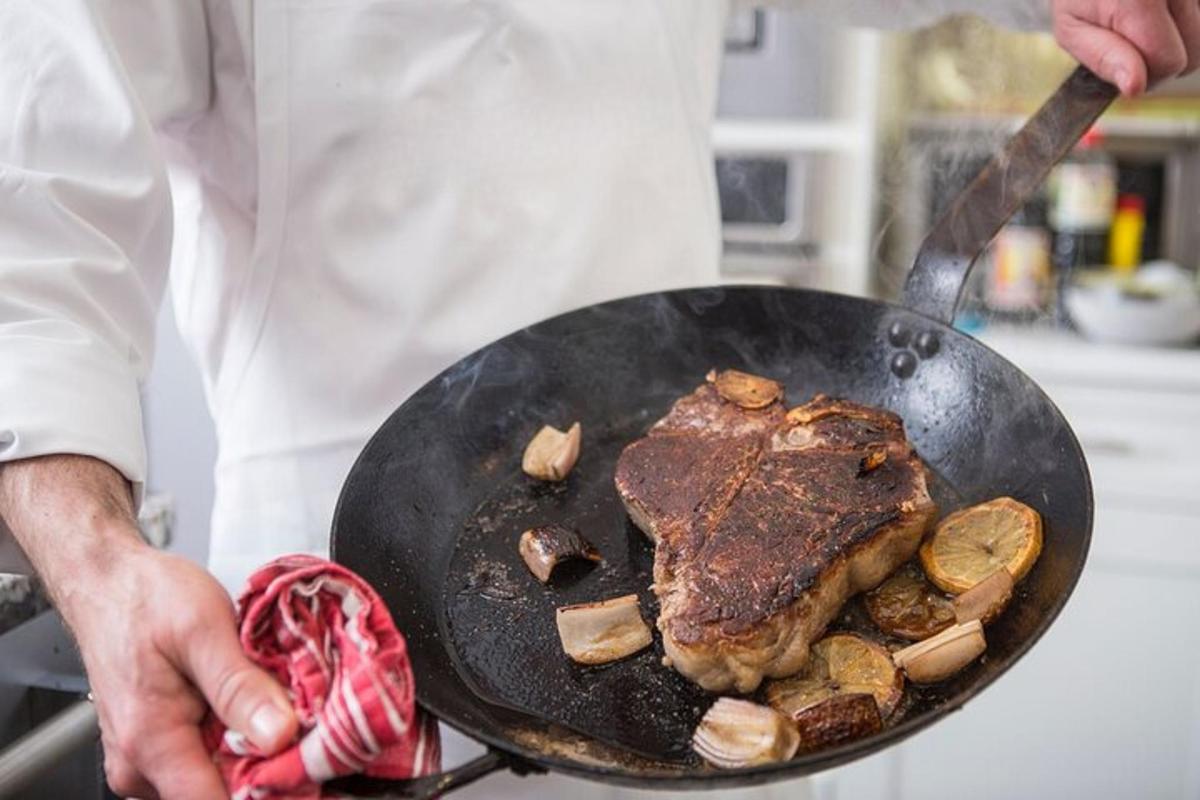un uomo che tiene in mano una padella con un pezzo di carne sopra