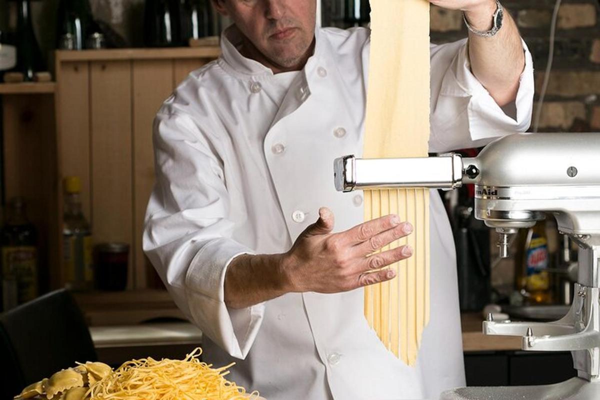 um homem em uma cozinha preparando macarrão com uma batedeira