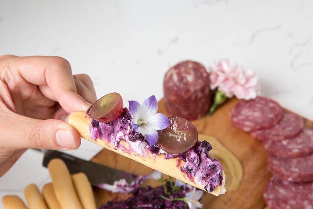 Una mano sosteniendo un trozo de comida con uvas y fruta.