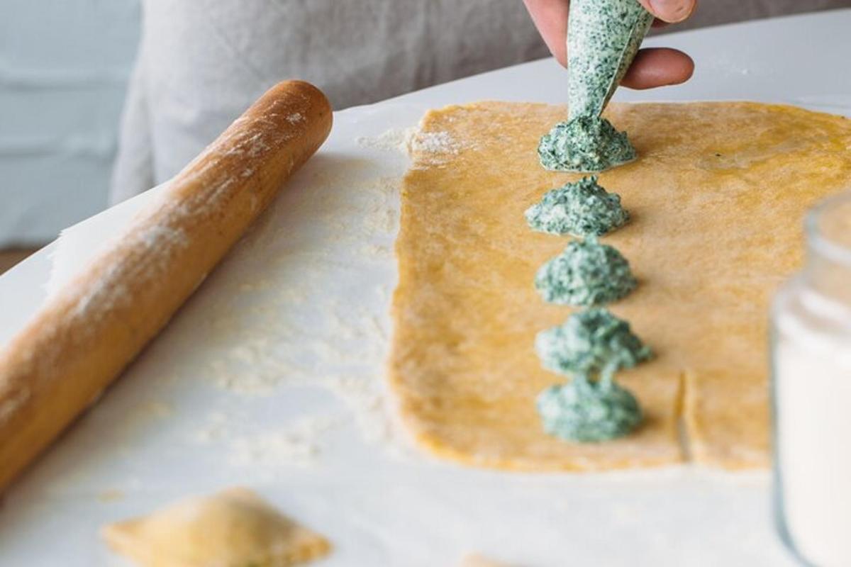 o persoană pune pesto pe o bucată de pâine
