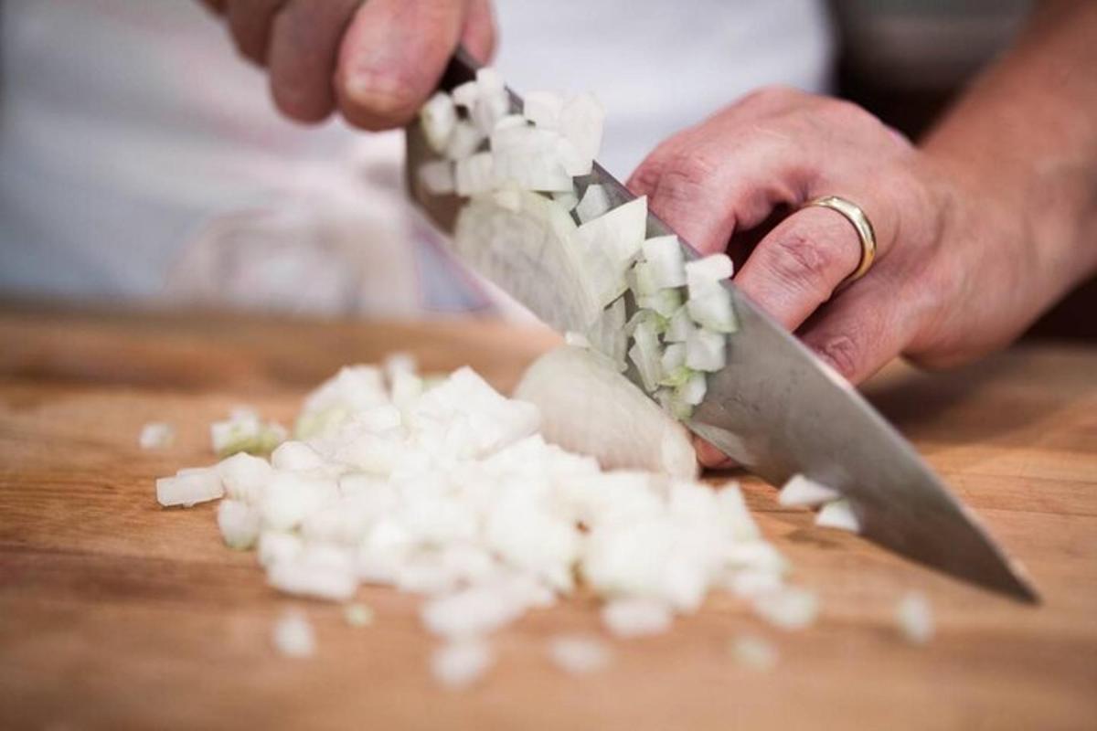 una persona cortando cebollas en una tabla de cortar con un cuchillo