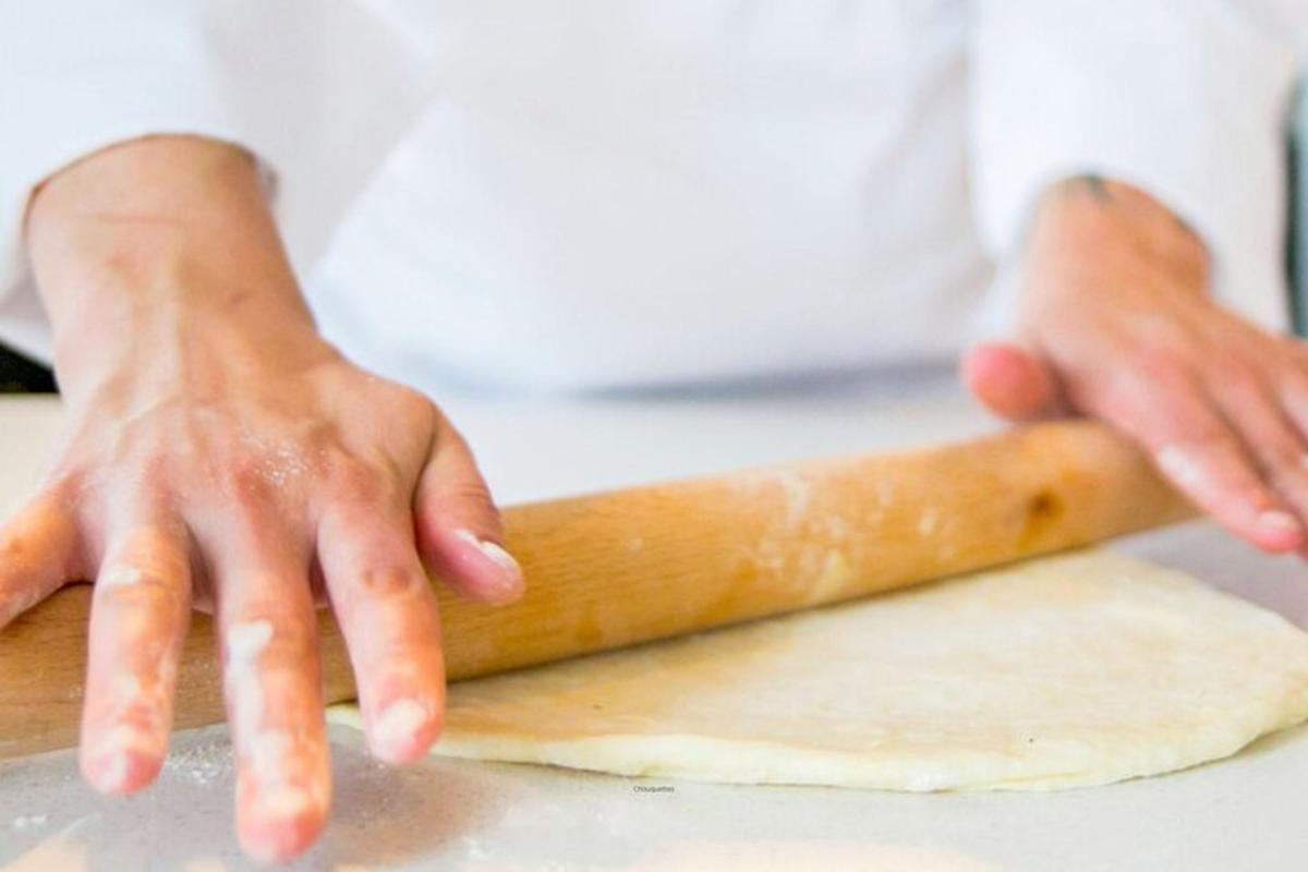 uno chef tiene in mano un pezzo di pasta su un bancone