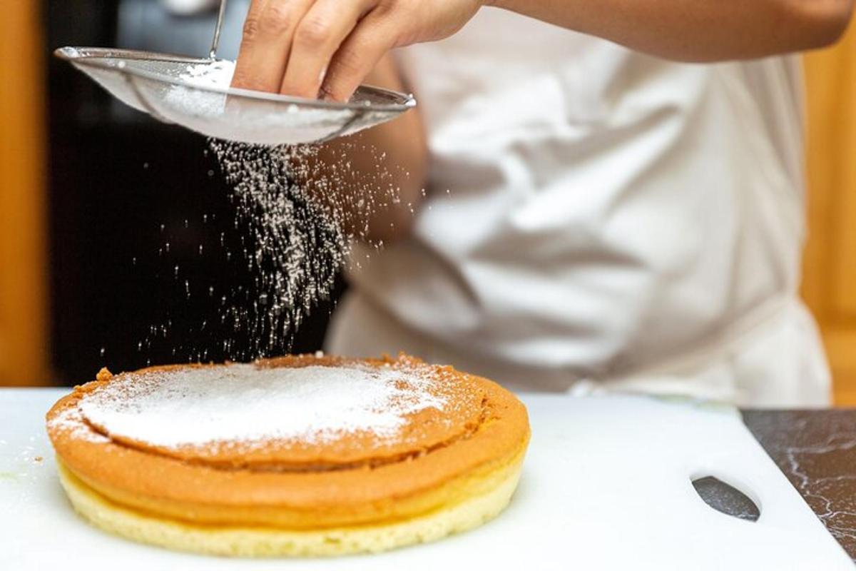 una persona sta cospargendo di zucchero a velo un dolce