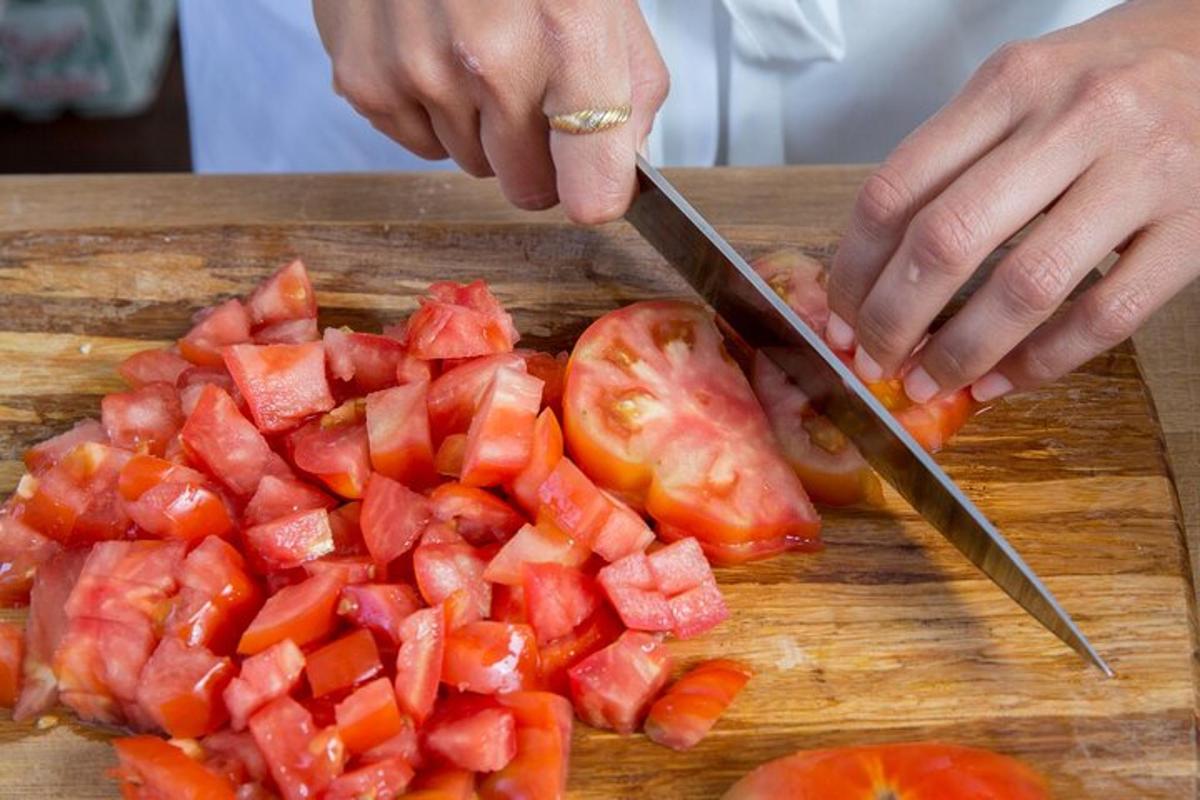 una persona che taglia i pomodori su un tagliere con un coltello