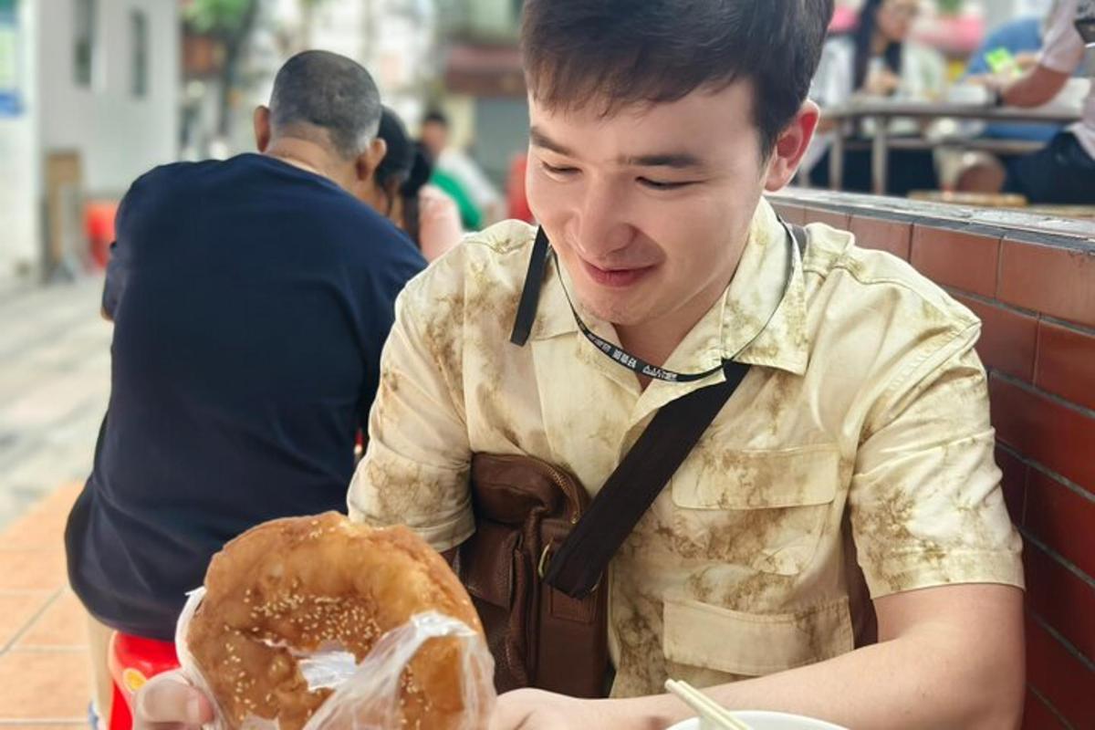 a young man sitting at a table eating a sandwich