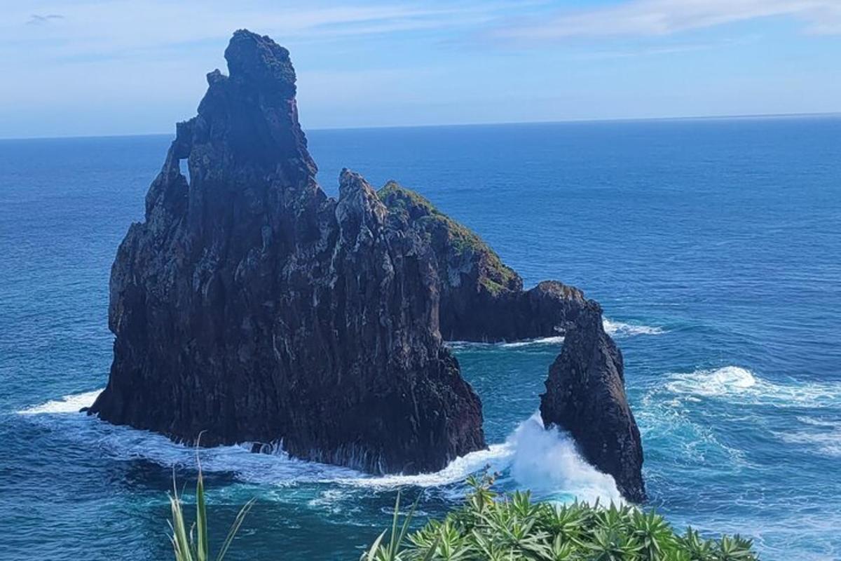 una grande formazione rocciosa nell'oceano con onde