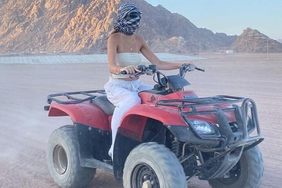Un hombre conduciendo un vehículo todo terreno rojo en la playa.