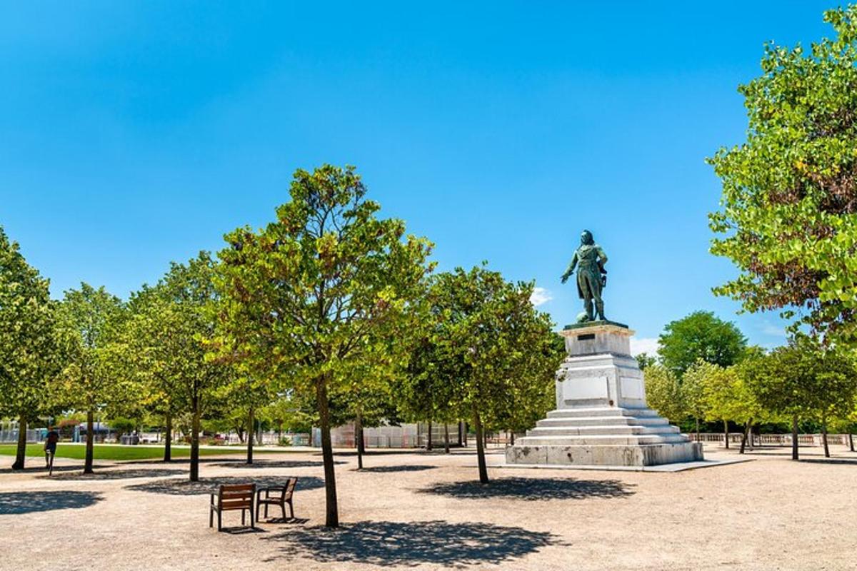 a statue in a park with two benches and trees
