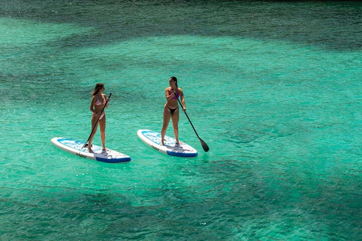 due donne in costume da bagno stanno facendo paddle boarding in acqua