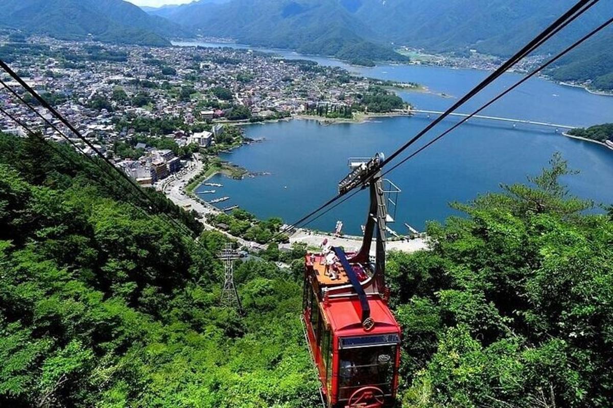 bir şehre bakan bir dağa tırmanan kırmızı bir teleferik