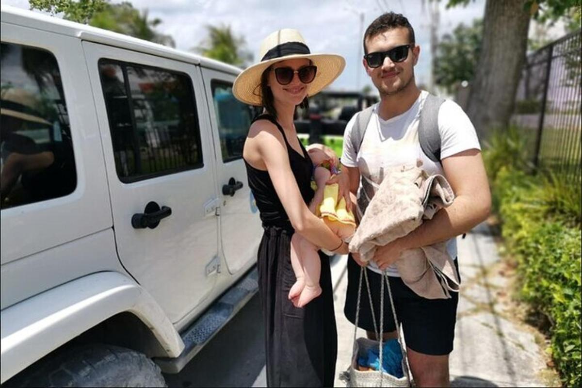 un uomo e una donna che tengono in braccio un bambino accanto a un furgone