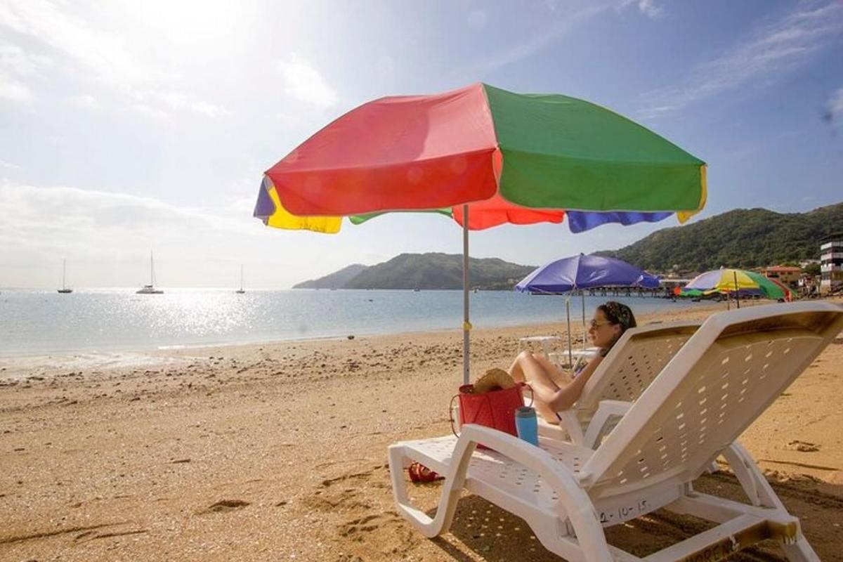 một người phụ nữ ngồi trên ghế dưới một chiếc ô trên bãi biển