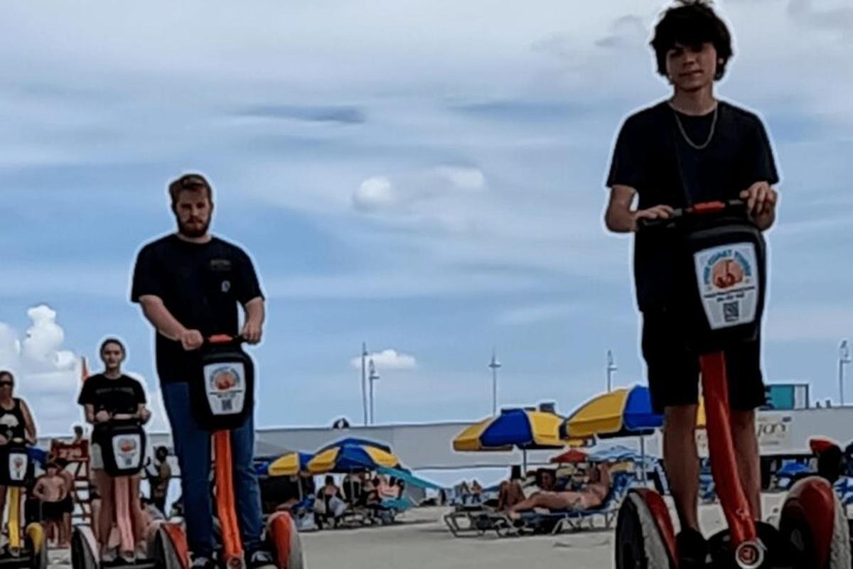 a group of young men riding scooters on the beach