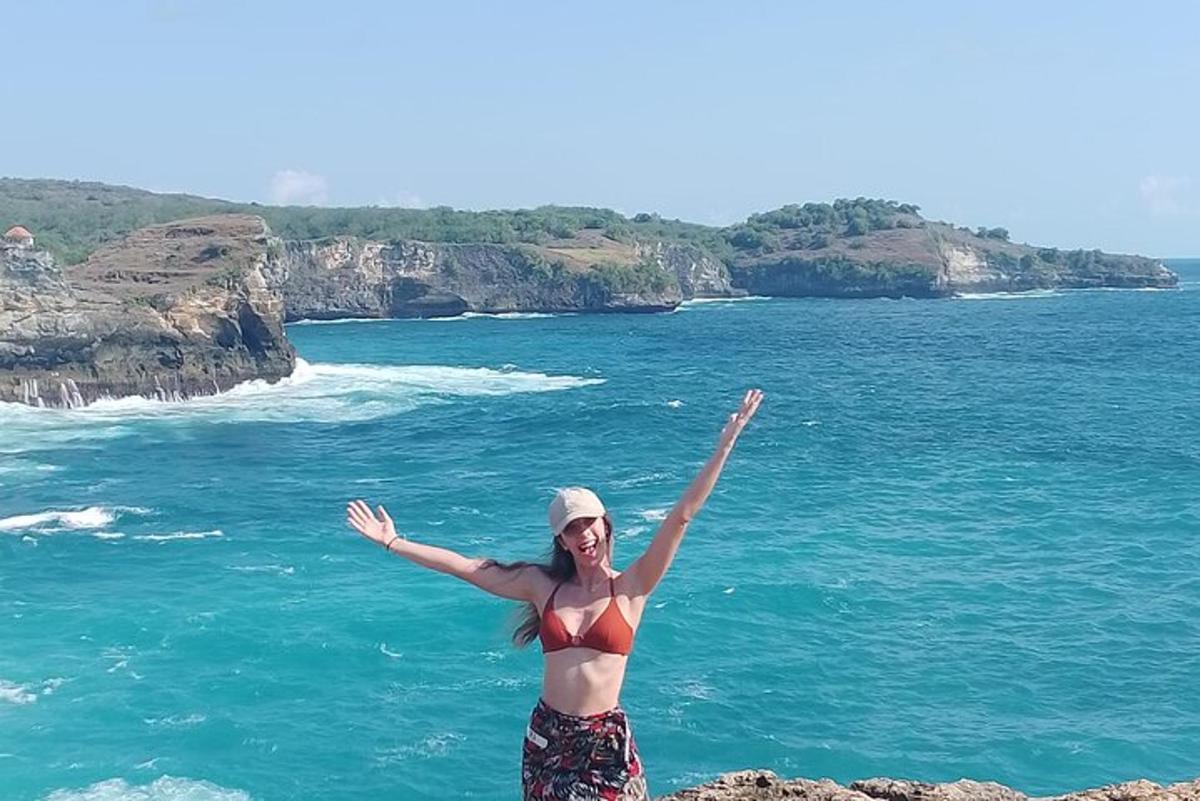 ženska v bikiniju stoji na pečini blizu oceana