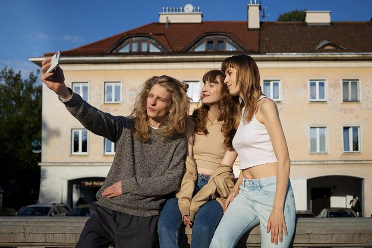 tři dívky sedící na zdi a fotící se s frisbee