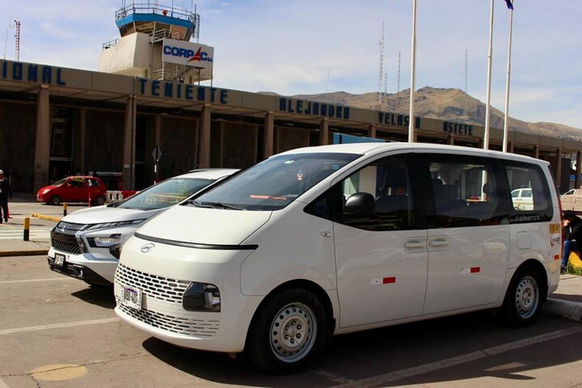 bir havaalanının önüne park edilmiş iki beyaz minibüs
