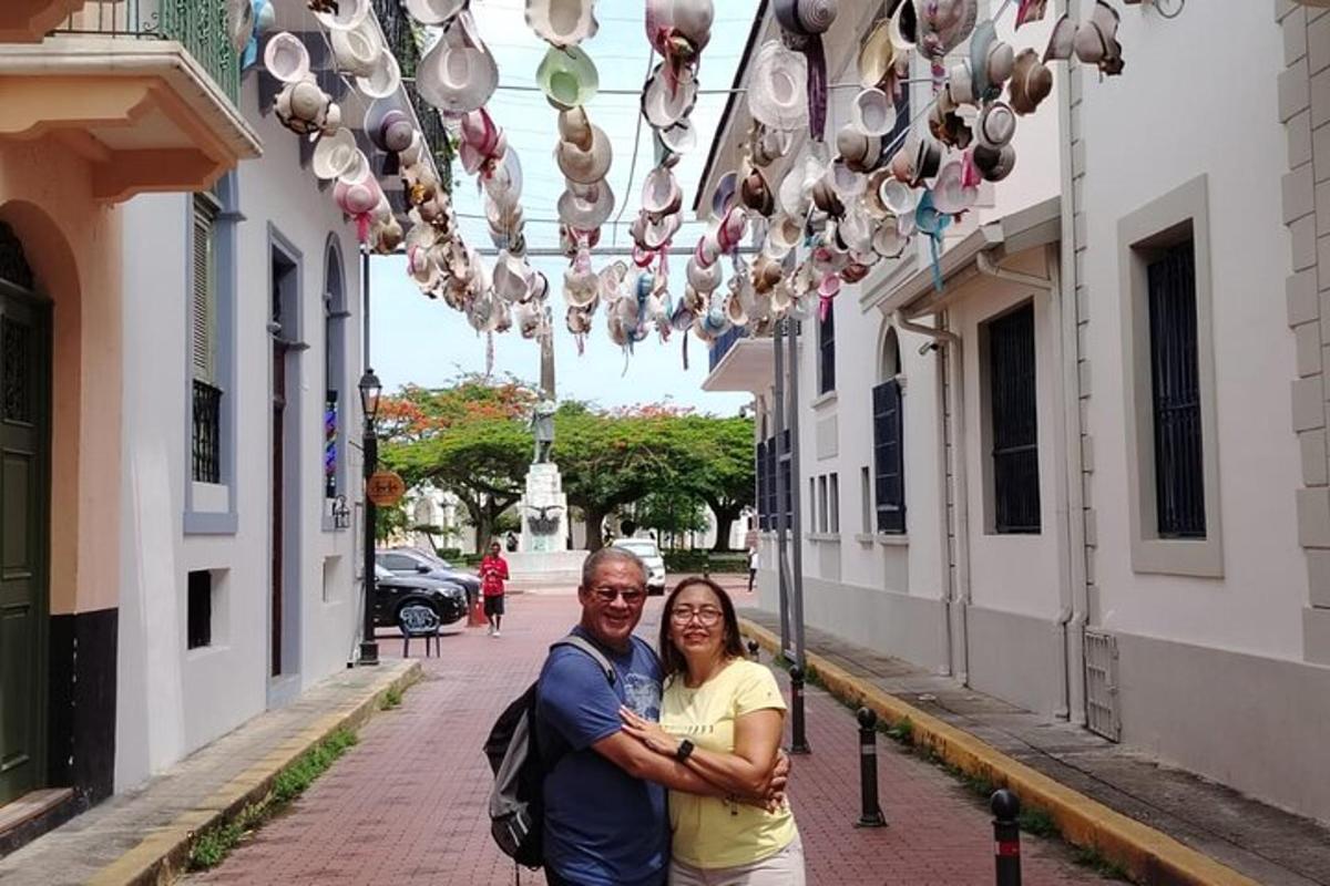 um homem e uma mulher parados em uma rua sob uma série de luzes