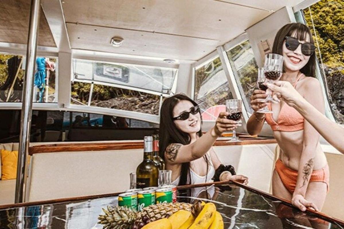 tiga wanita memegang gelas anggur di atas perahu