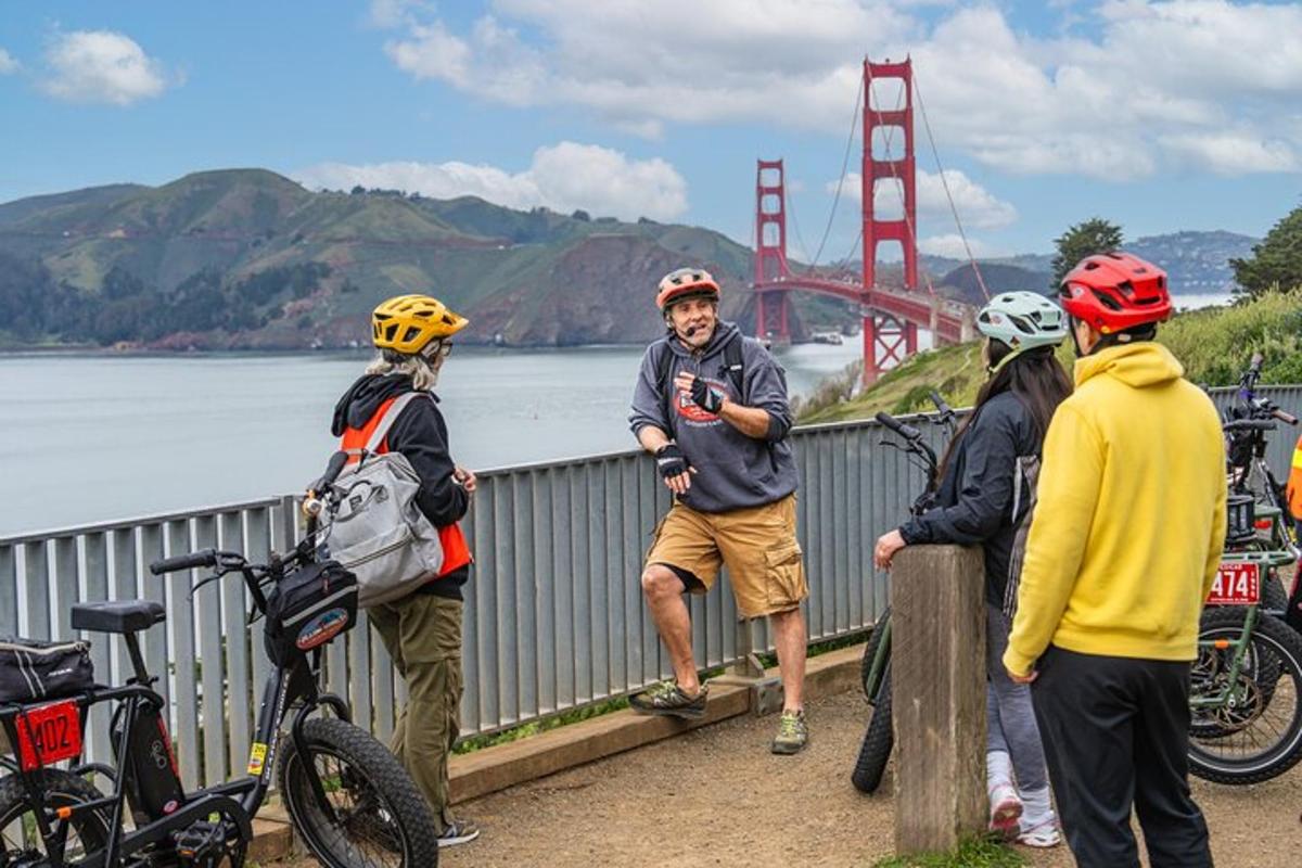 skupina ljudi, ki stojijo na mostu z mostom Golden Gate