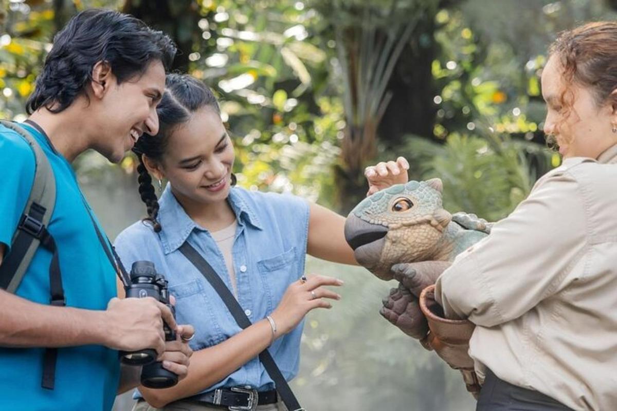 seorang wanita memegang burung hantu boneka sementara dua orang sedang mengambil gambar
