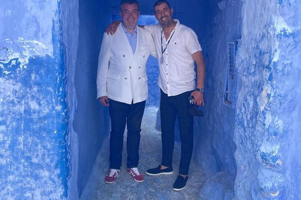two men standing next to each other in a blue wall
