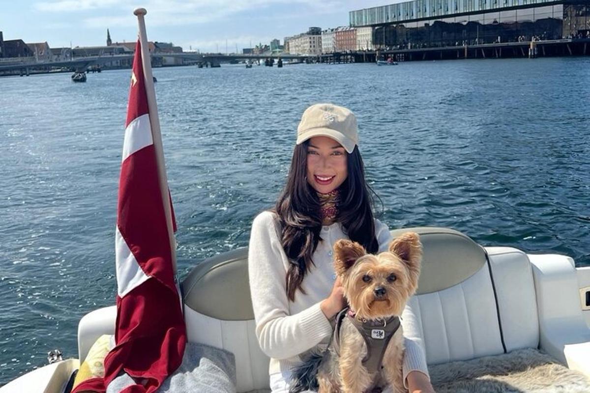 a woman sitting on a boat with a small dog