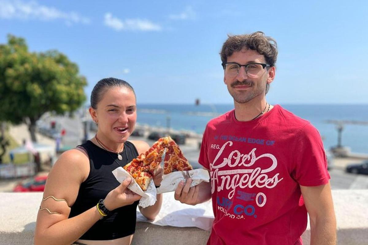 a man and a woman holding a slice of pizza