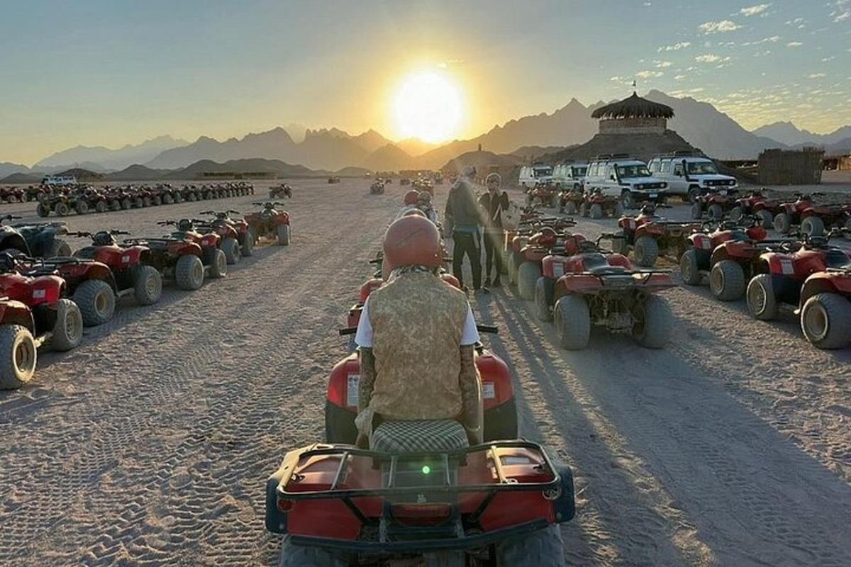 sekumpulan orang menunggang basikal quad di padang pasir