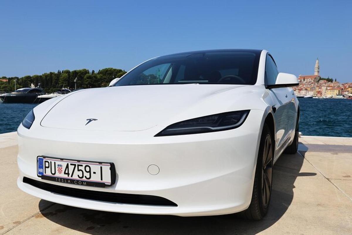bílé auto Tesla zaparkované u vody