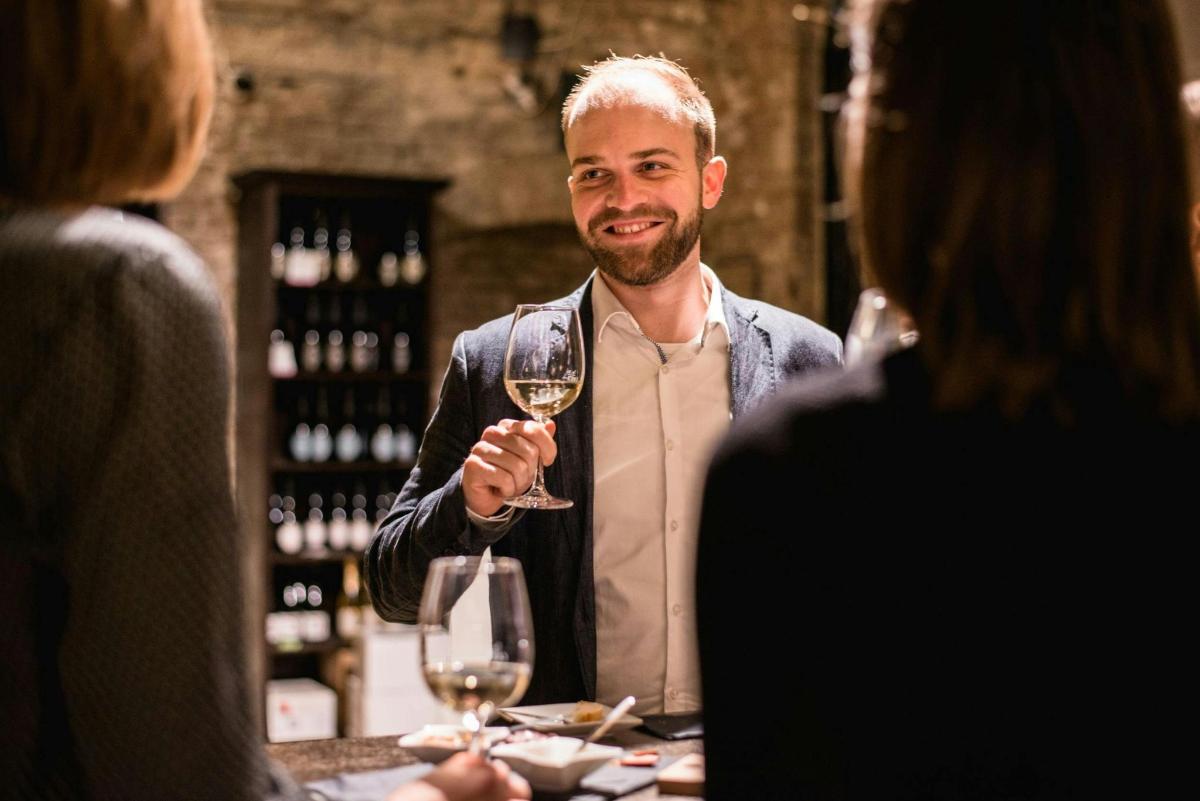 ein Mann hält ein Glas Wein an einem Tisch