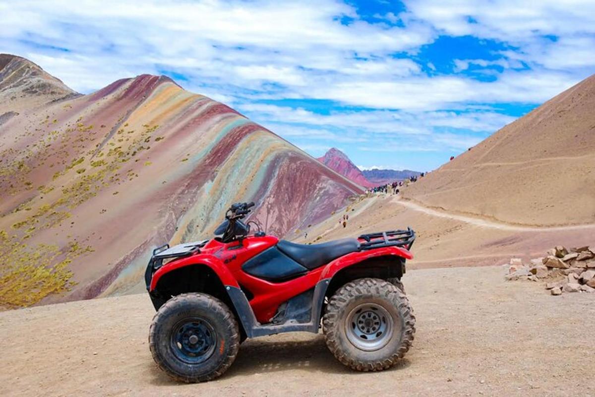 en rød ATV parkert i ørkenen med fjell