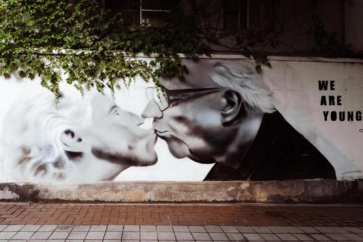 un muro con un murale di una coppia che si bacia