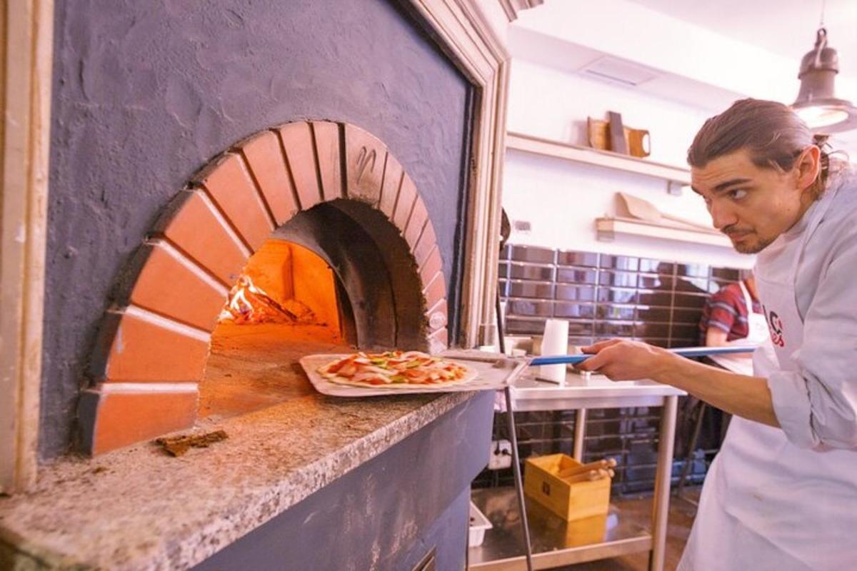 muž dává pizzu do pece na pizzu