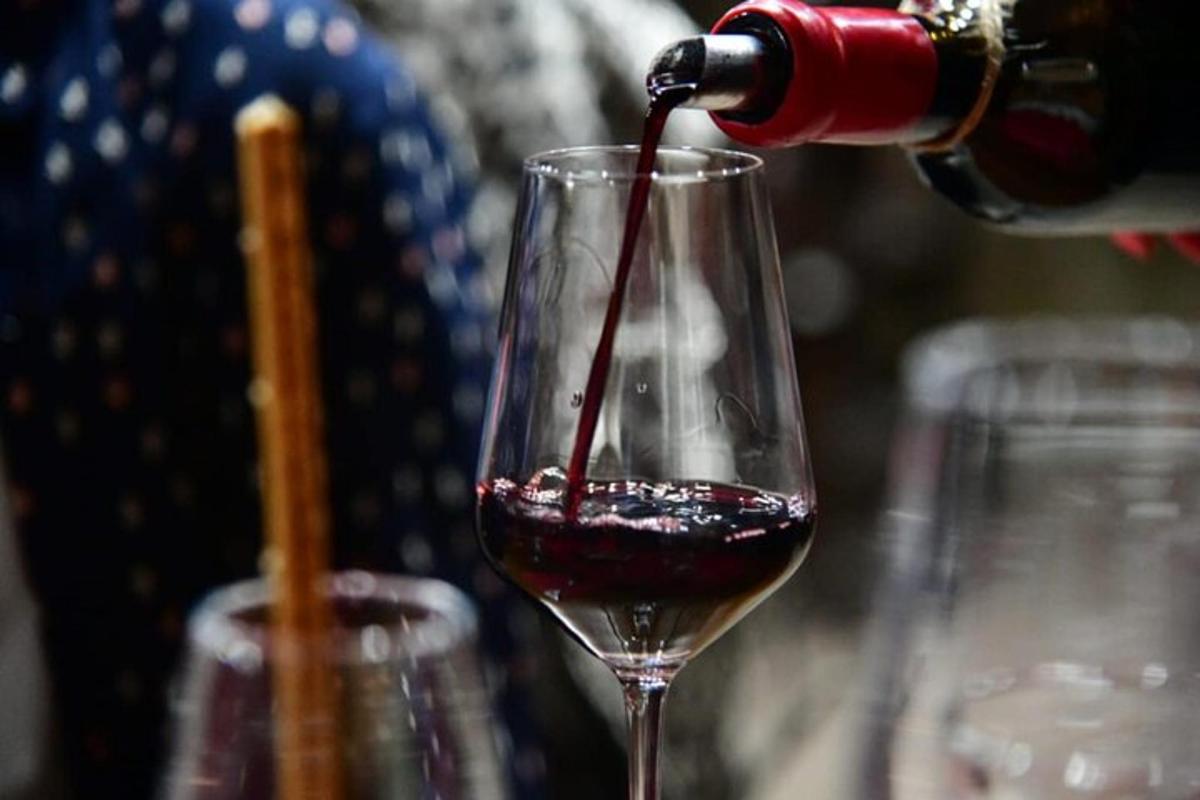 a person pouring red wine into a wine glass