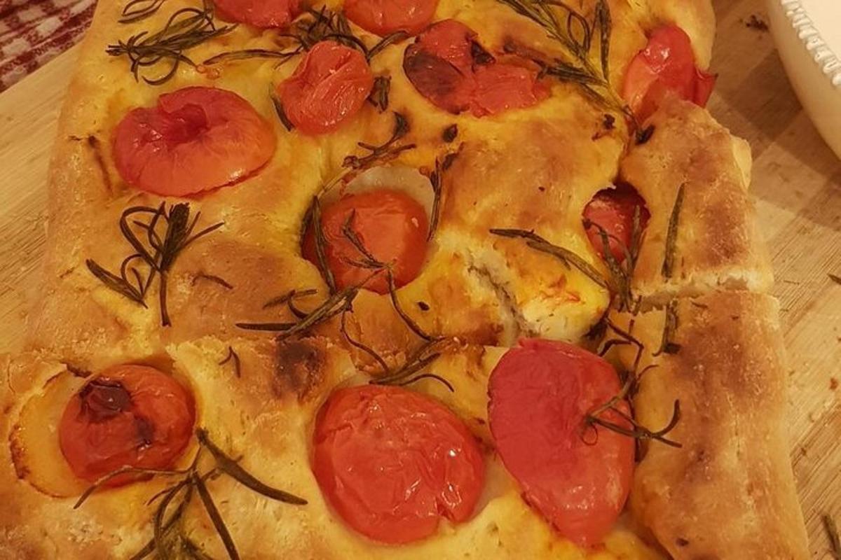 a pizza with tomatoes on it sitting on a table