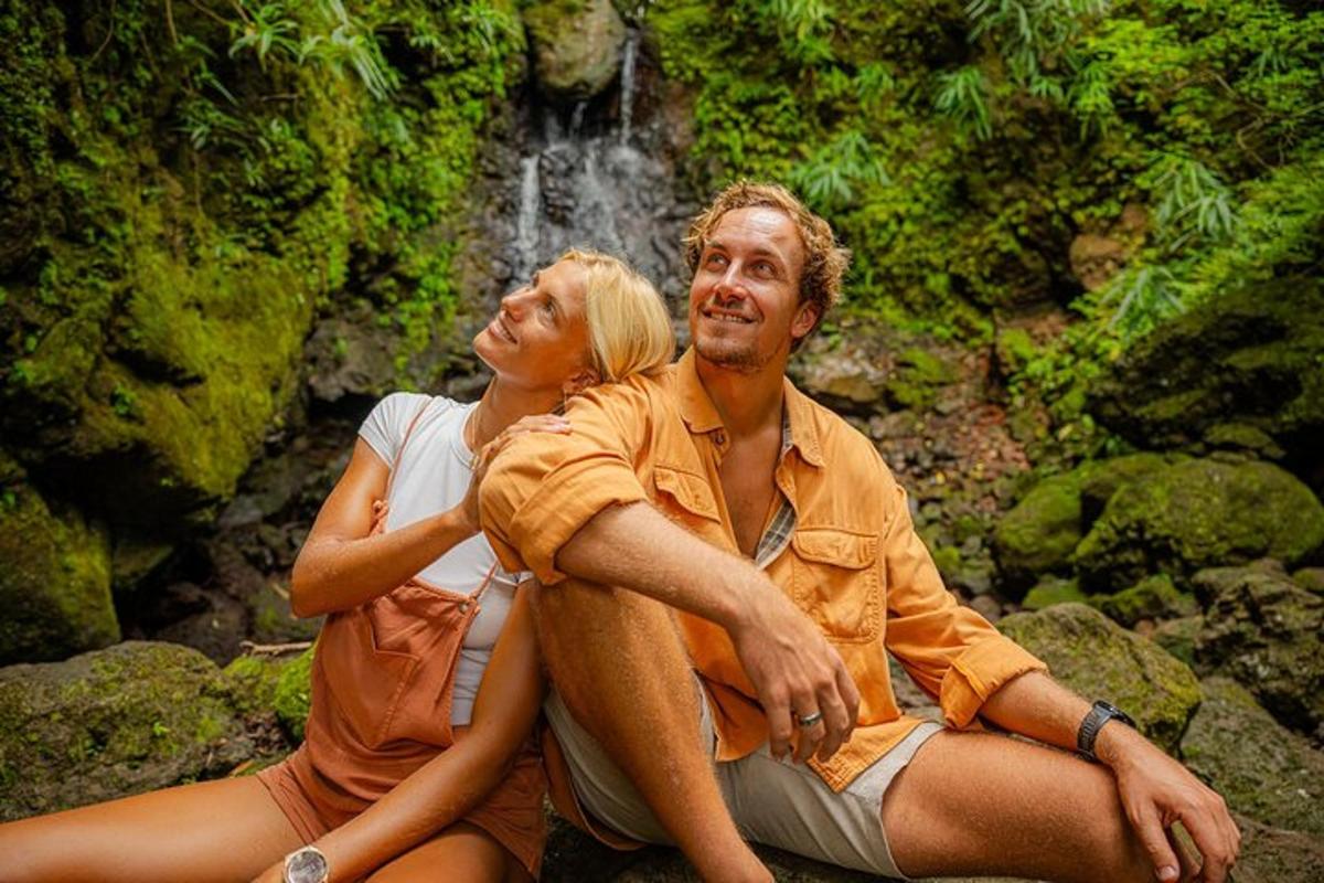 un home i una dona asseguts sobre roques davant d'una cascada